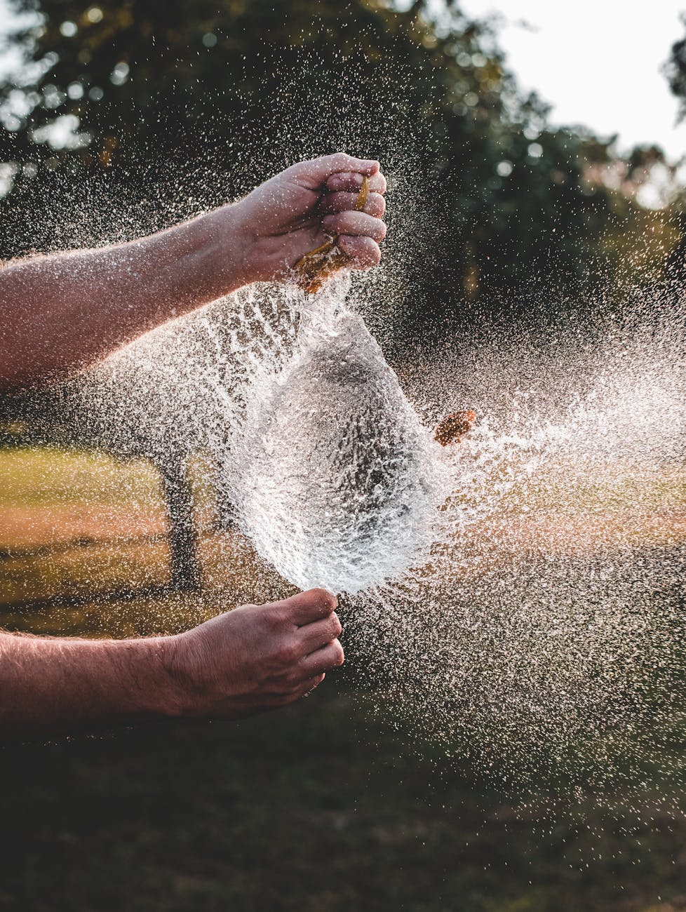 person bursting balloon with water